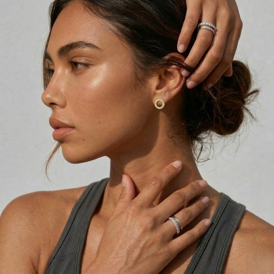 Woman wearing gold circle earrings with a neutral background.