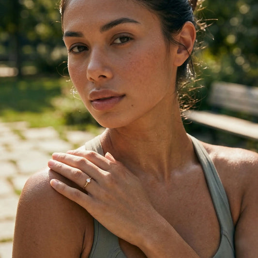 Woman in a green top standing outdoors and wearing a ring with a small diamond.
