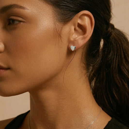 Close-up of a woman wearing a heart-shaped earring with a neutral background.