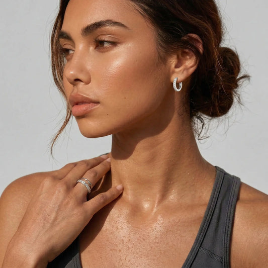 Woman wearing a silver hoop earring with clear stones and a gray top.