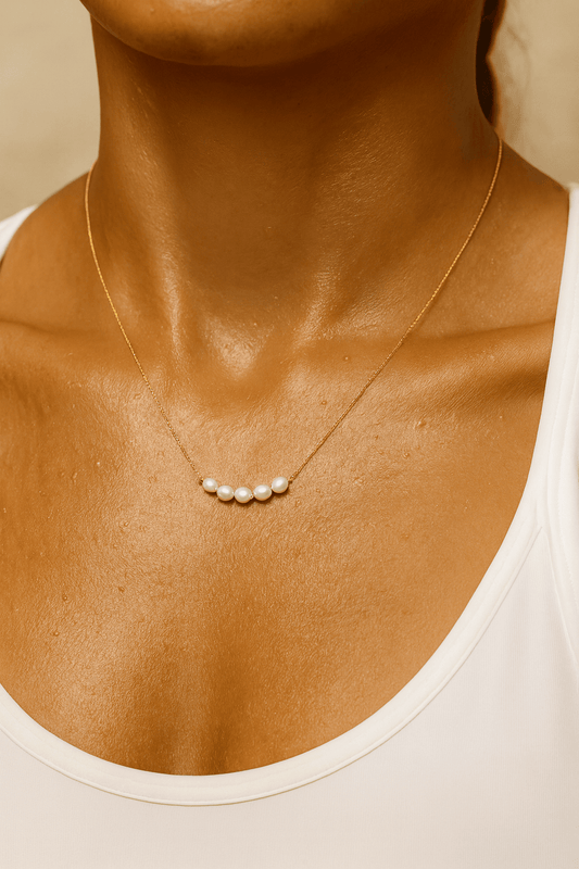Gold pearl necklace on a women wearing a white top