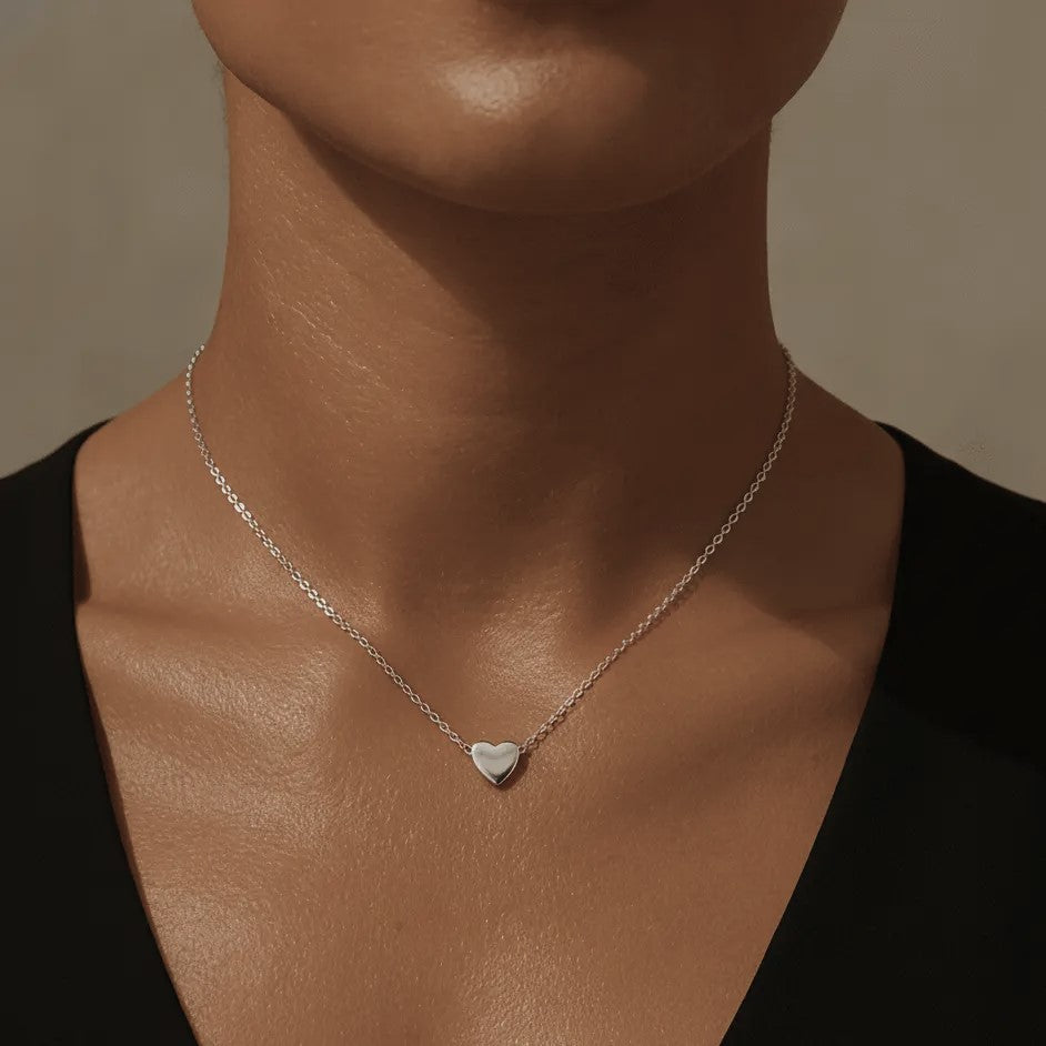 Silver heart pendant necklace on a woman's neck.