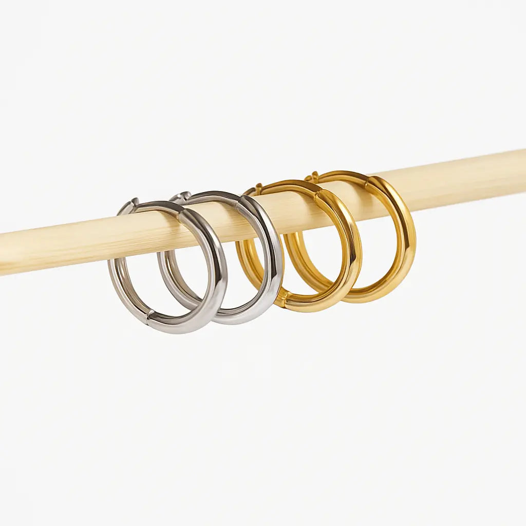 Two pairs of hoop earrings, silver and gold on a white background.
