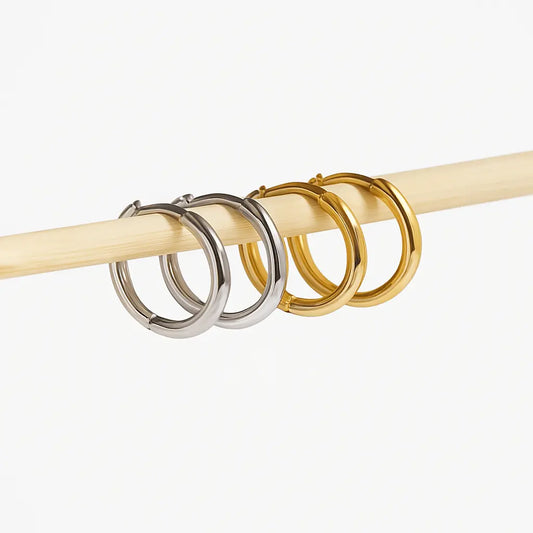 Two pairs of hoop earrings, silver and gold on a white background.