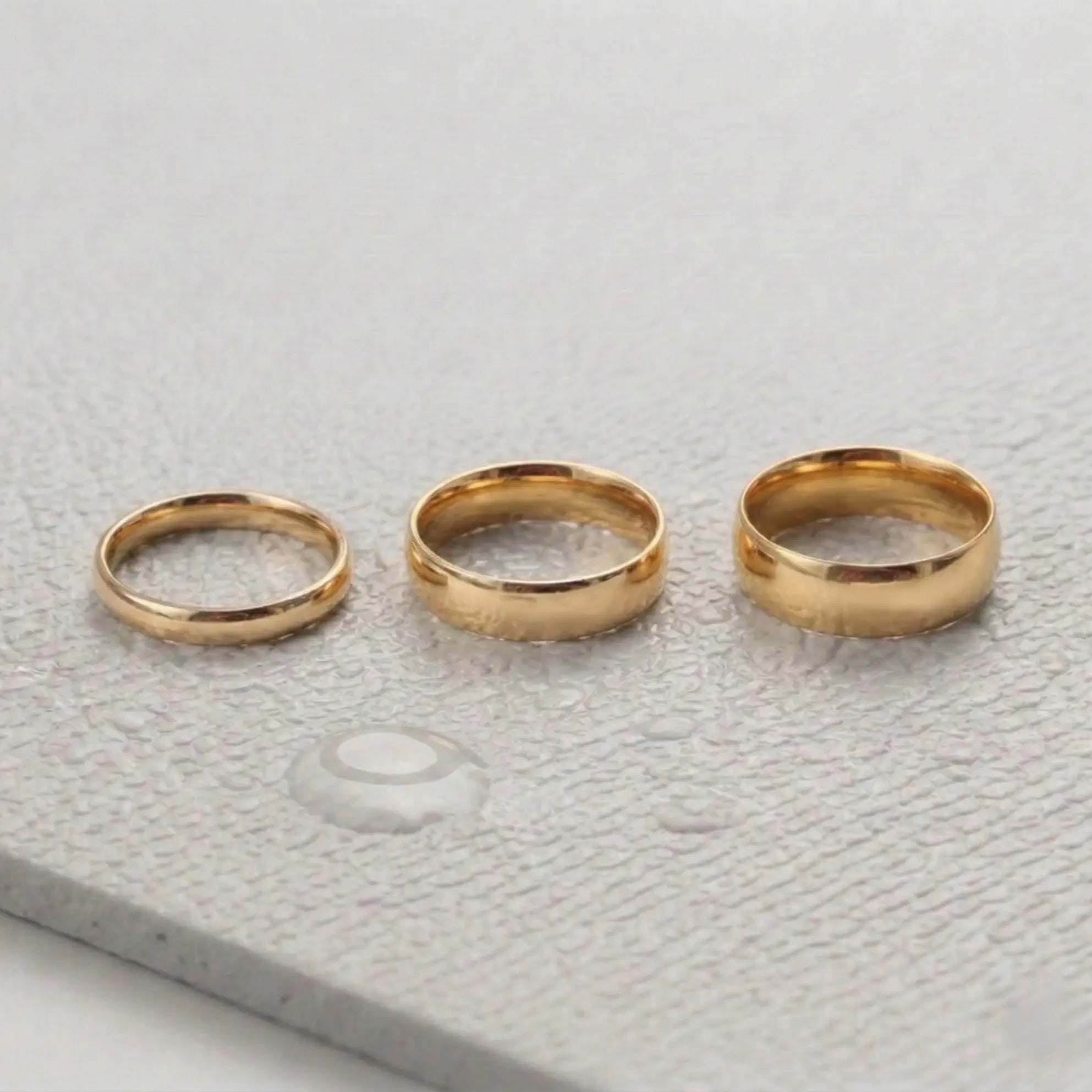 Three gold rings on a light gray fitness mat.