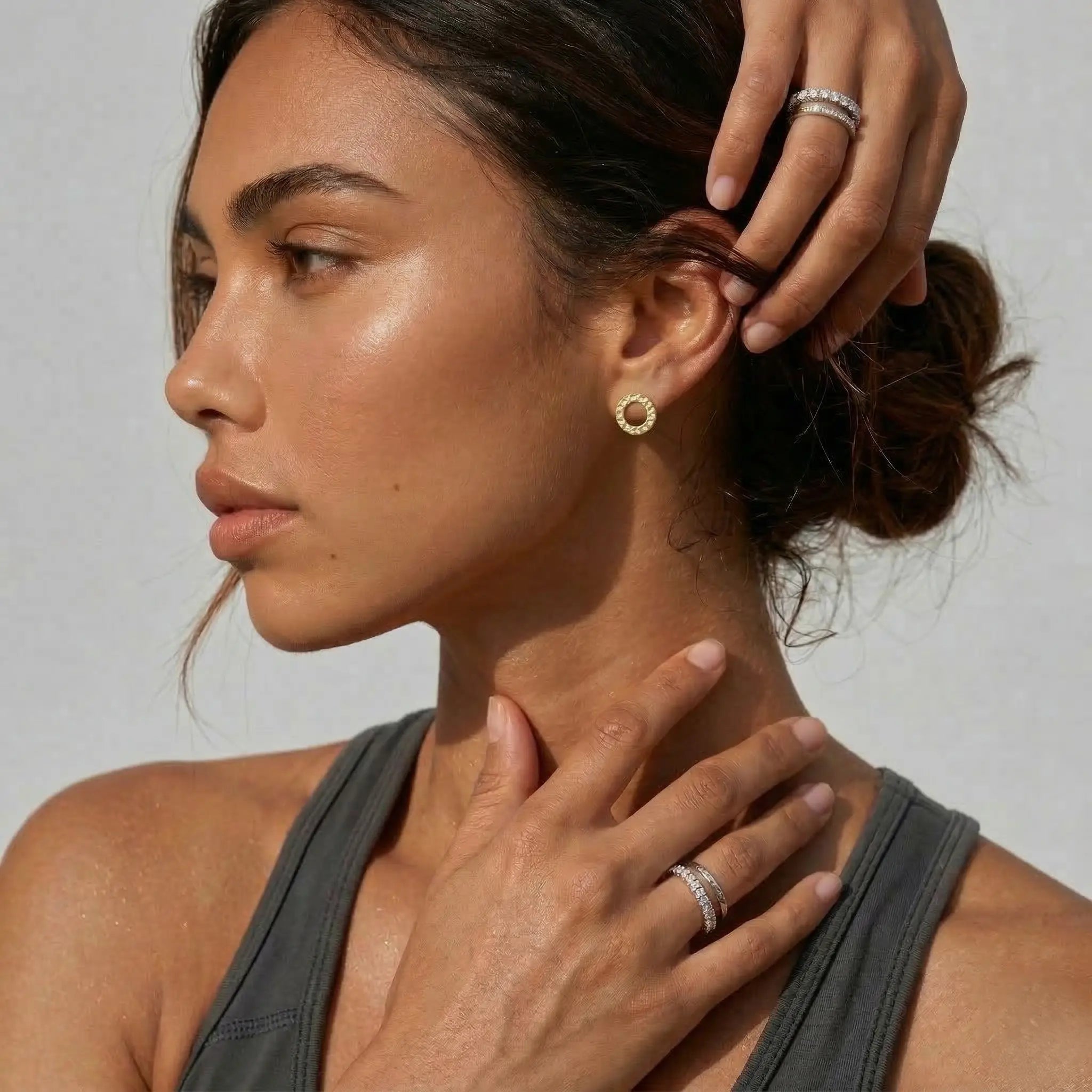 Woman wearing gold circle earrings with a neutral background.