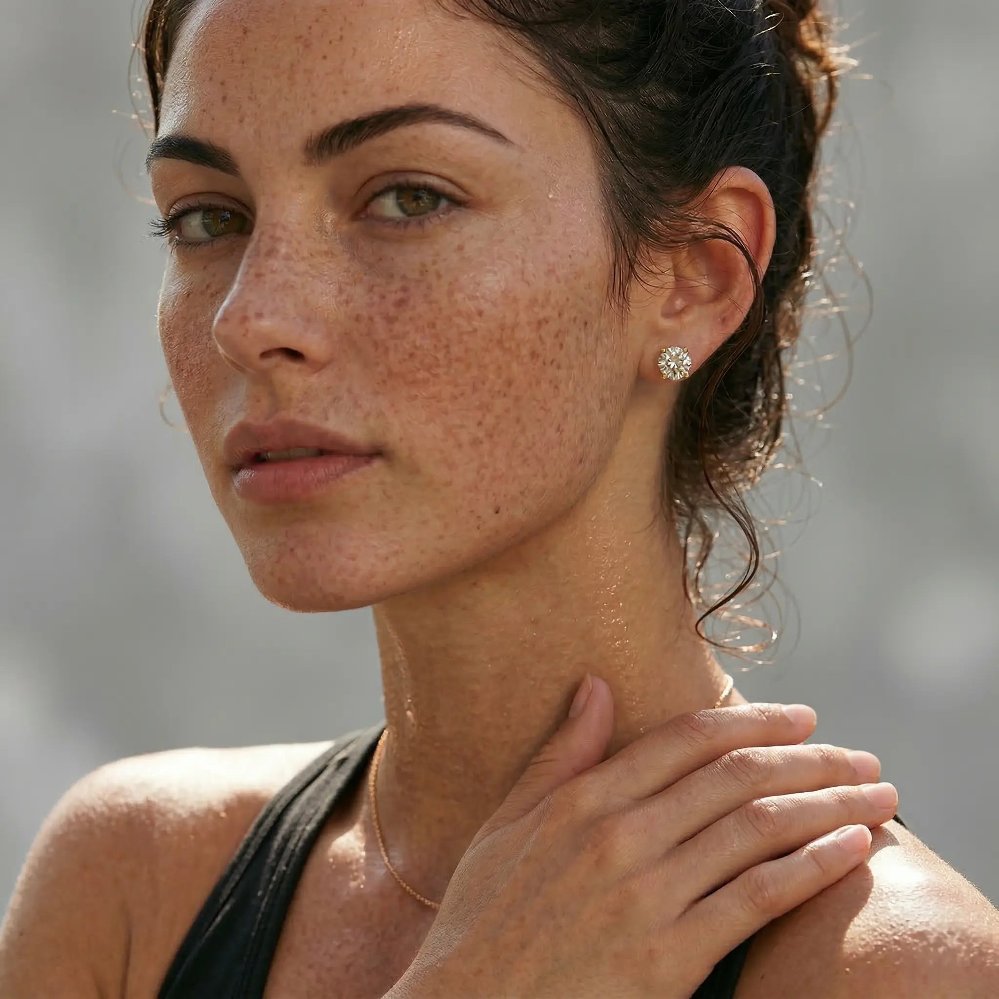 Close-up of a woman wearing a diamond earring with a black top.