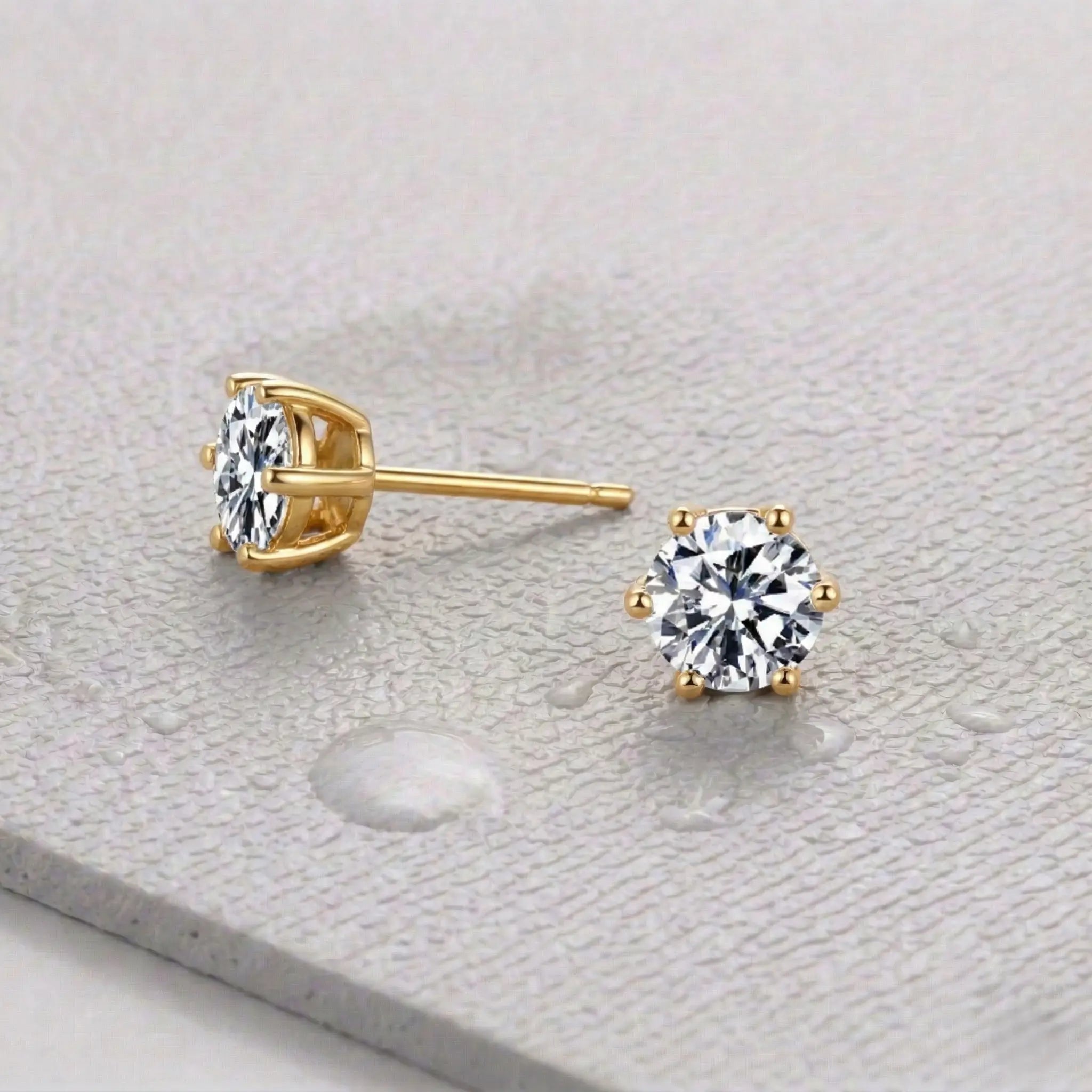 Pair of gold zirconia stud earrings on a light gray fitness mat.
