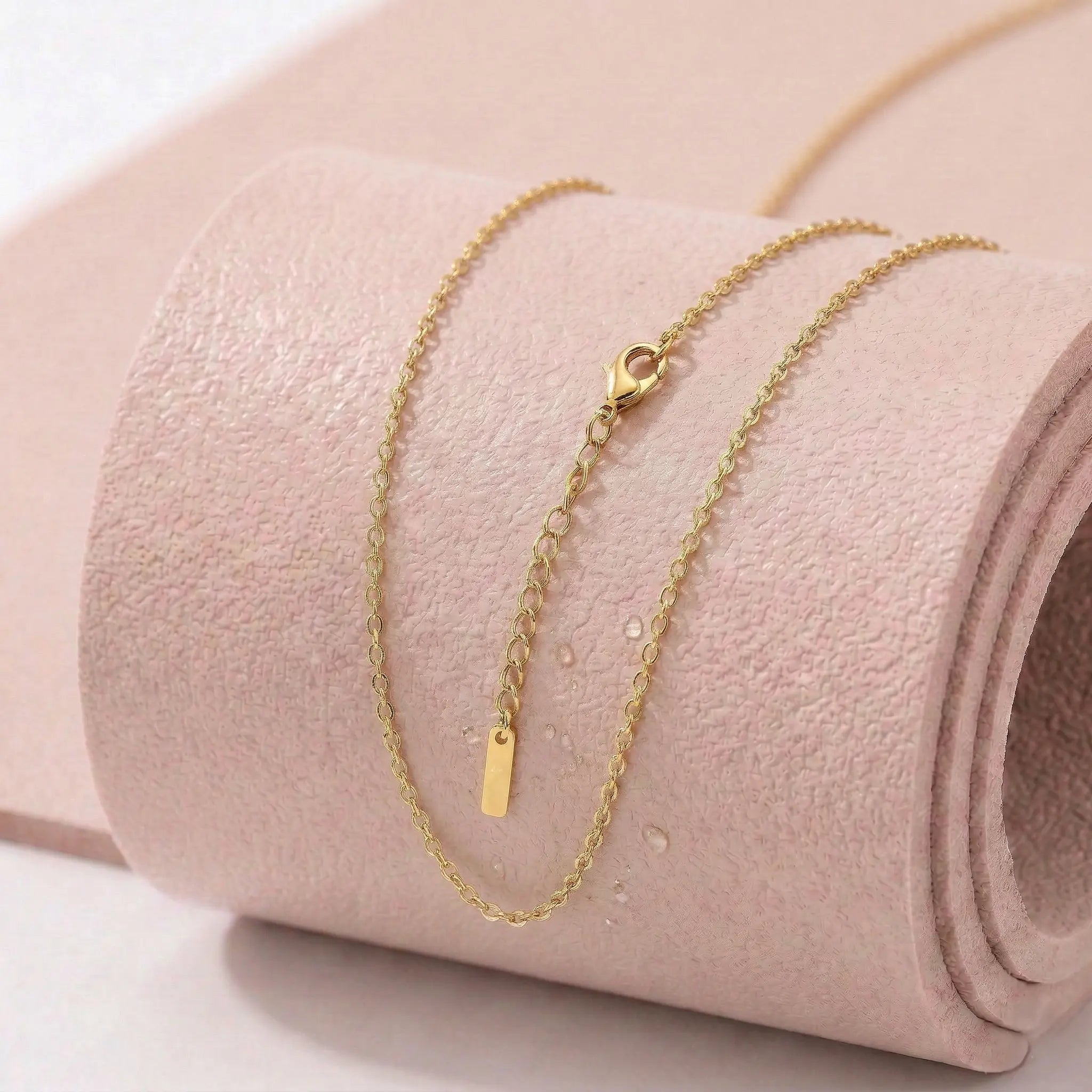 Gold stainless steel necklace on a light pink fitness mat. 