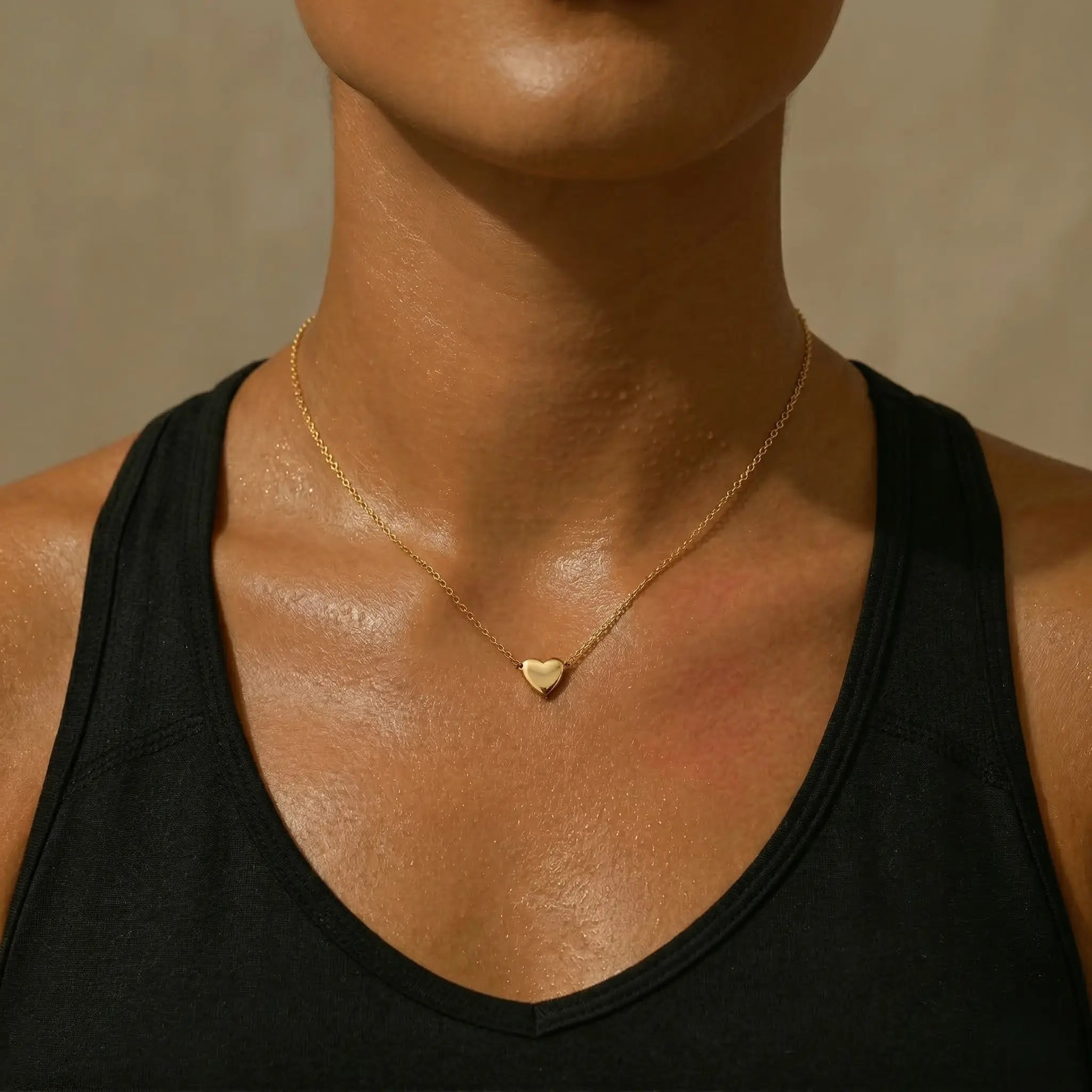 Gold waterproof heart pendant necklace worn by woman.