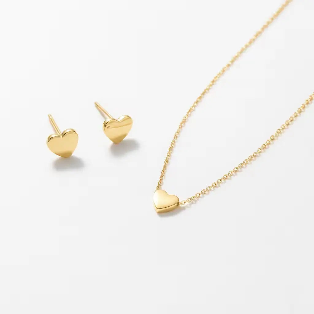 Gold heart-shaped necklace and matching stud earrings on a white background.