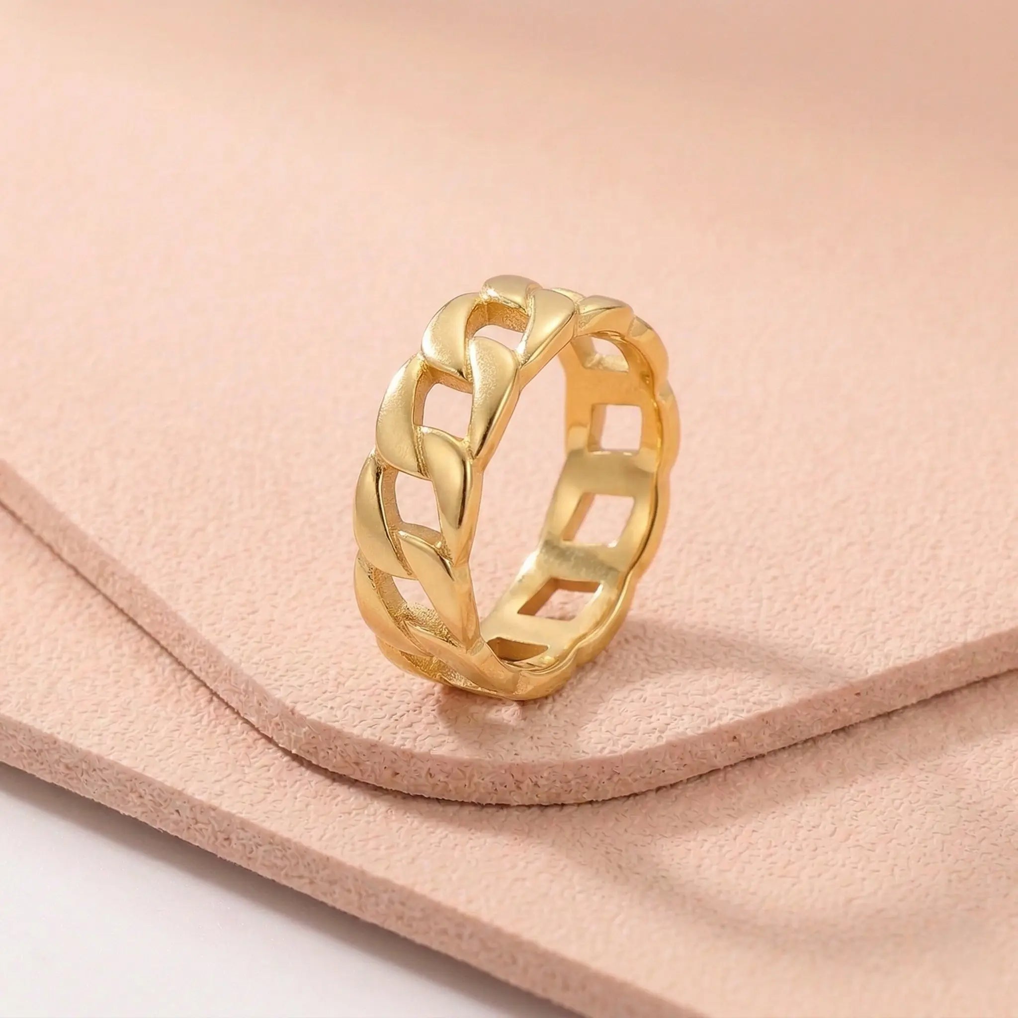 Gold stainless steel ring with a braided design on a light pink fitness mat.