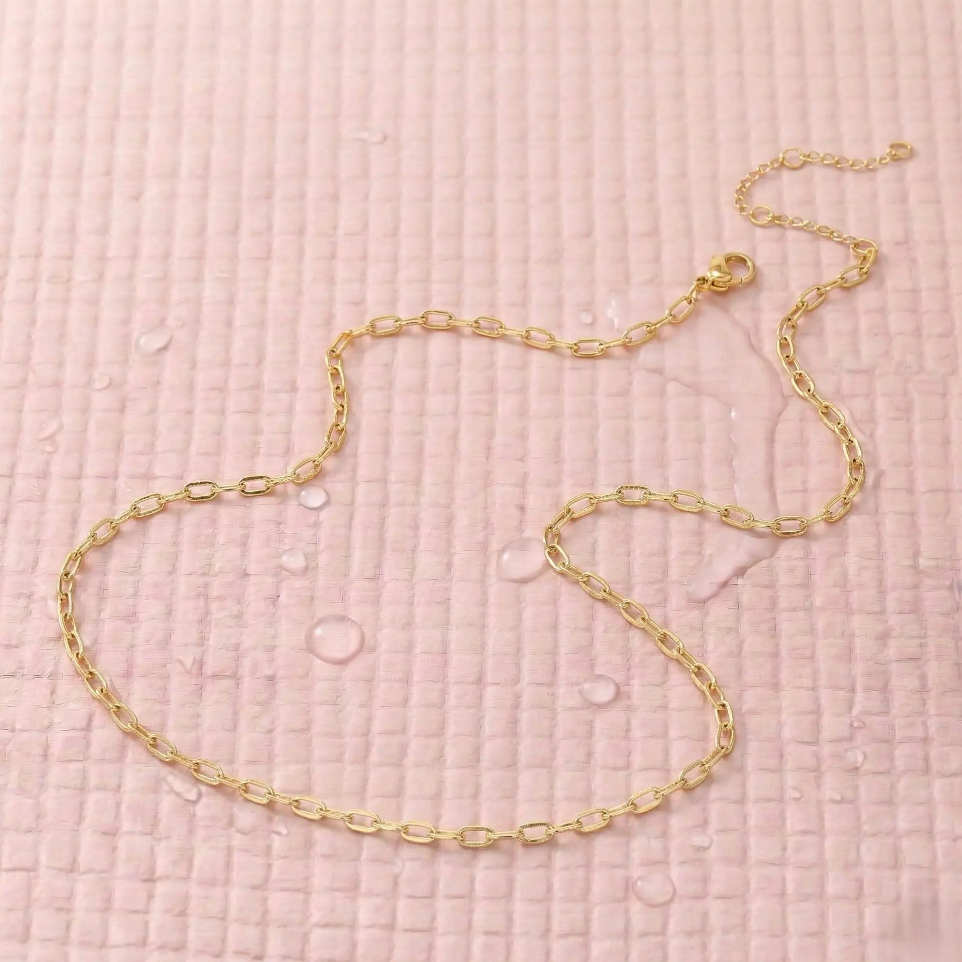 Gold-plated chain necklace on a pink fitness mat.