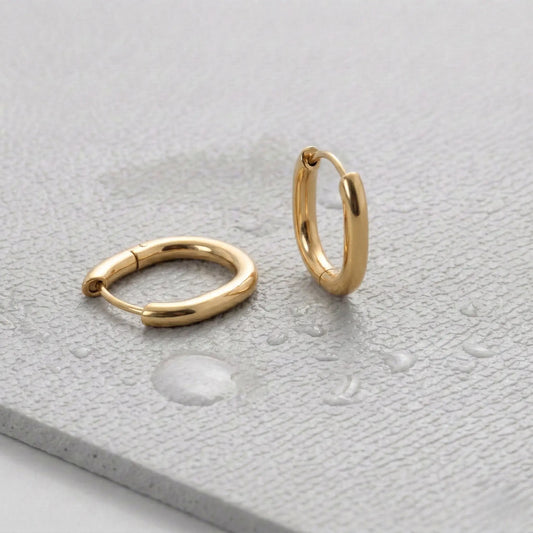 Pair of gold hoop earrings on a light gray fitness mat.