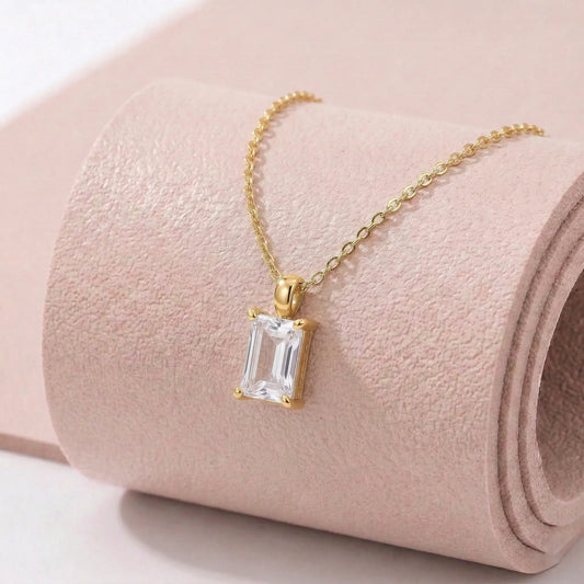 Gold necklace with a diamond pendant on a pink textured fitness mat.