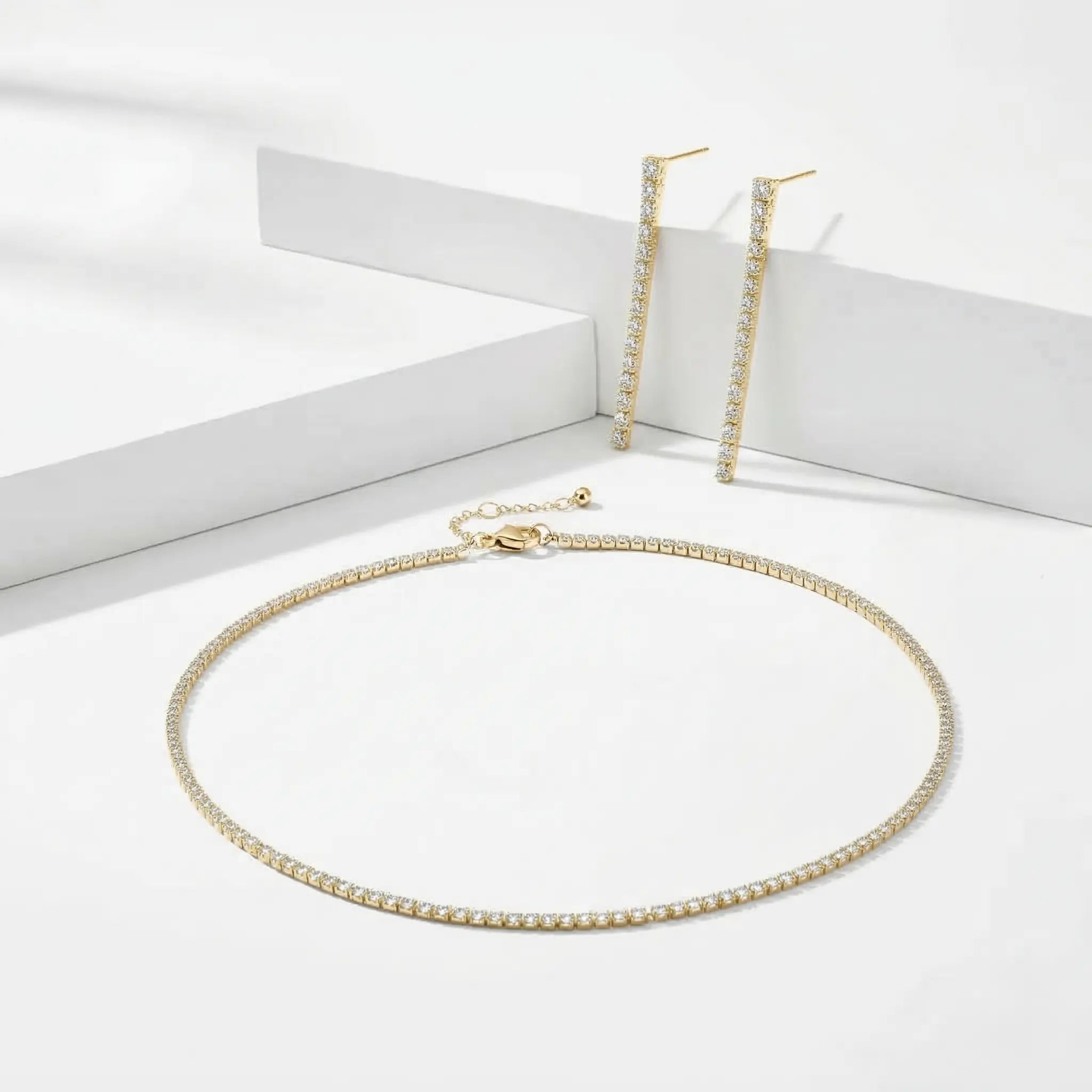Gold zirconia necklace and matching drop earrings on a white background.