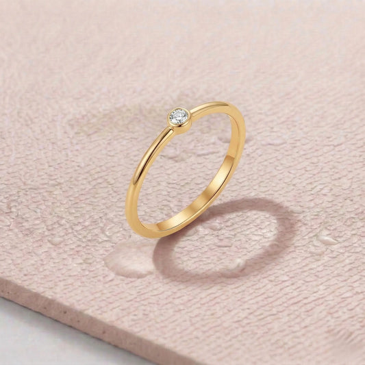 Gold ring with a diamond on a light pink fitness mat.