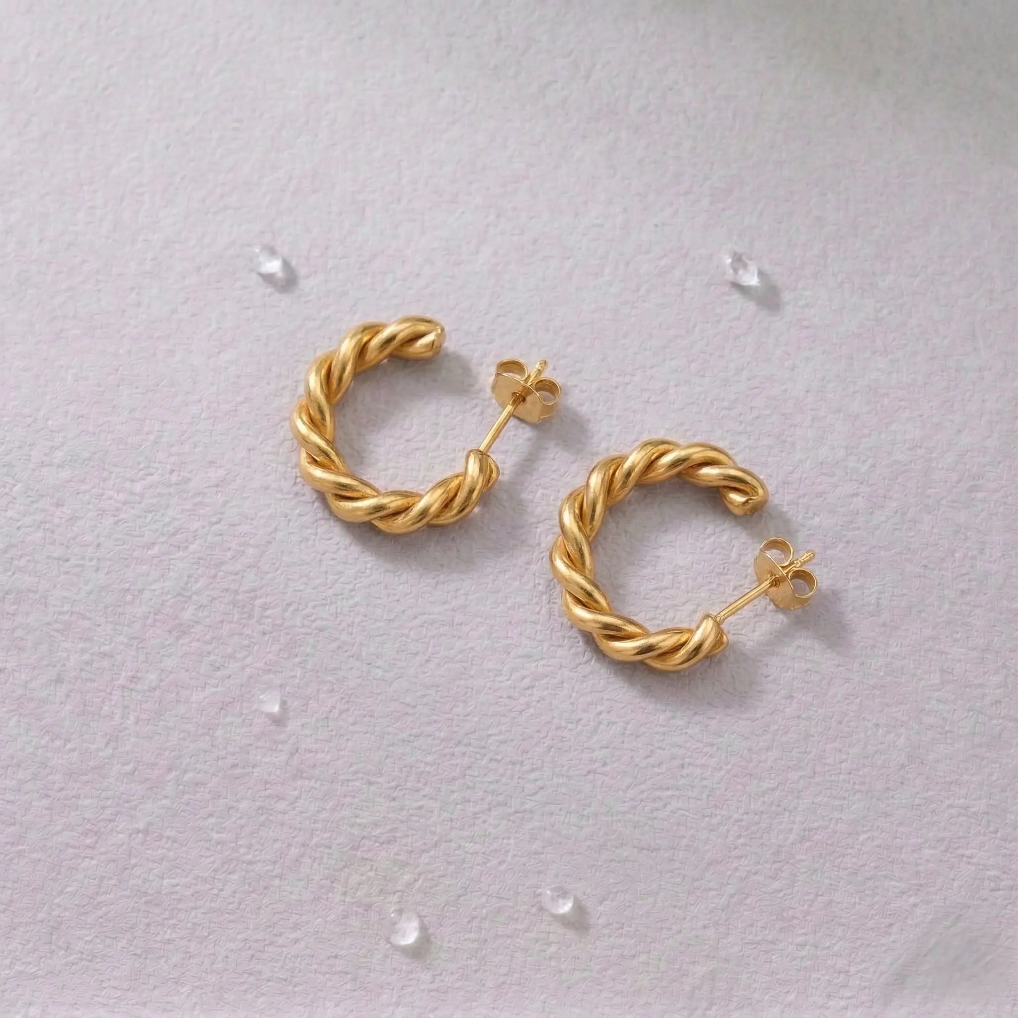 Pair of waterproof gold hoop earrings on a light gray background.