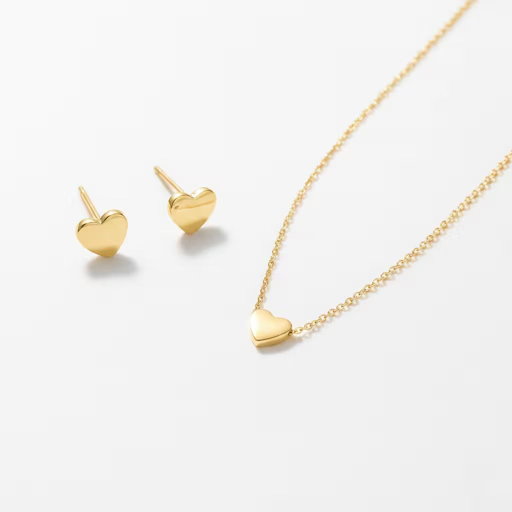 Gold heart-shaped necklace and matching stud earrings on a white background.