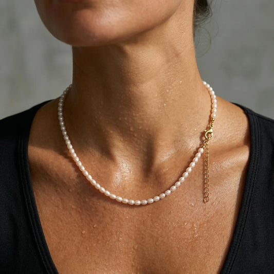 Pearl sweat resistant necklace worn by a woman with a neutral background.