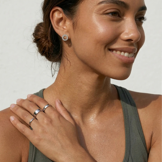 Woman wearing three silver rings with a neutral background.