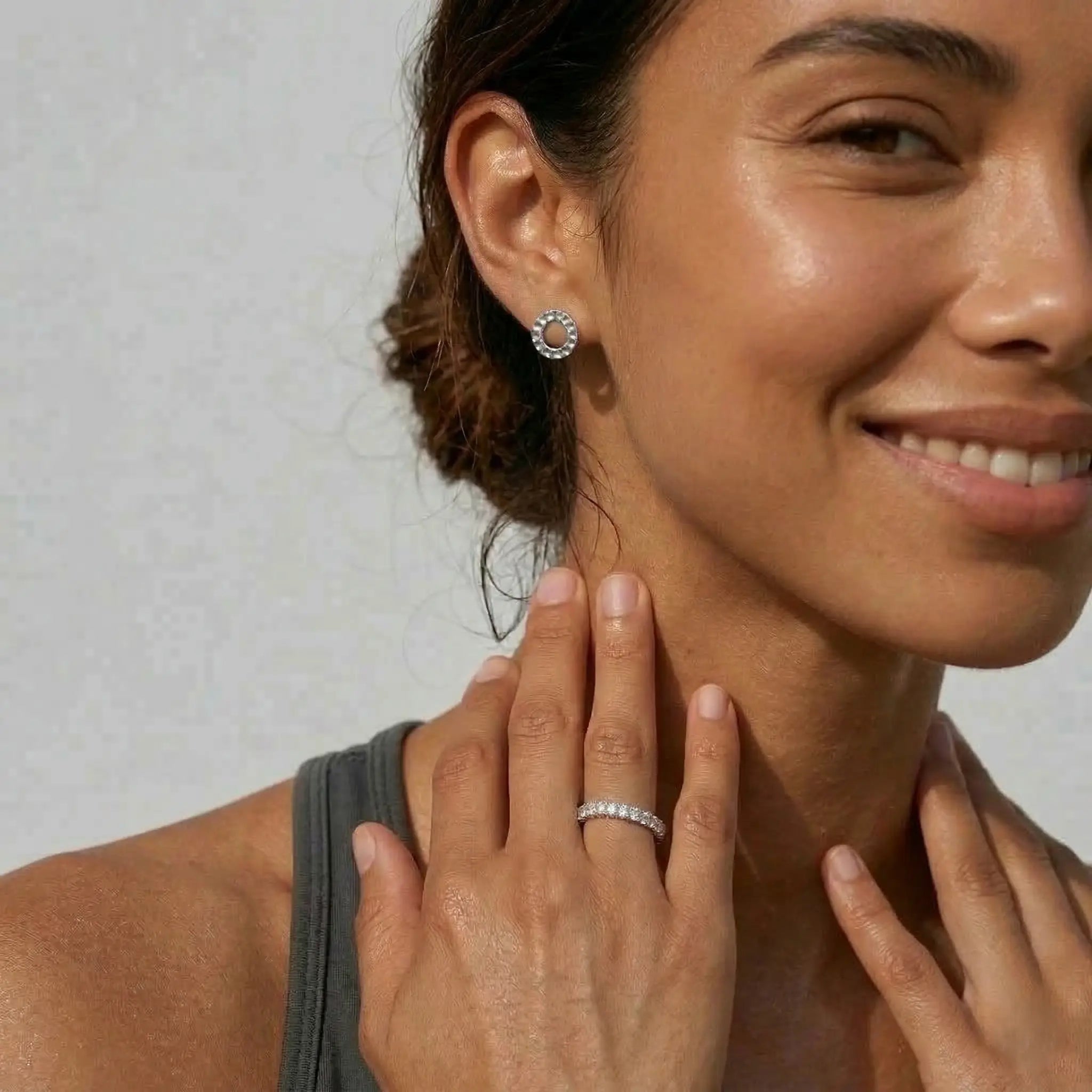 Woman wearing silver circle earrings with a neutral background.