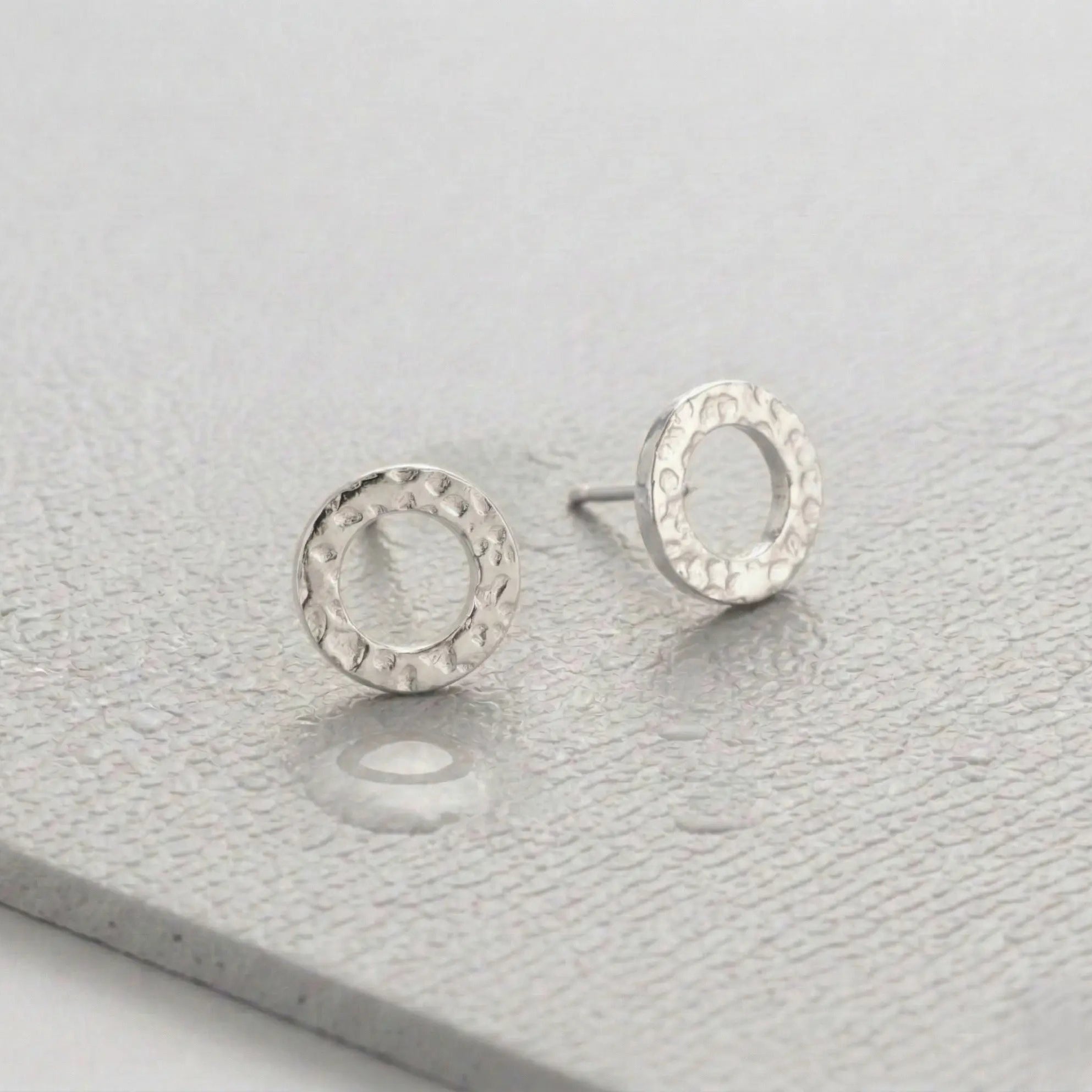 Waterproof silver circle earrings on a light gray fitness mat.