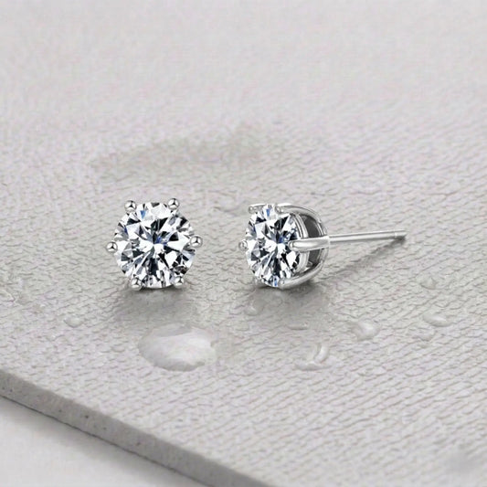 Pair of silver zirconia stud earrings on a light gray fitness mat.