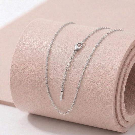 Silver stainless steel necklace on a light pink fitness mat.