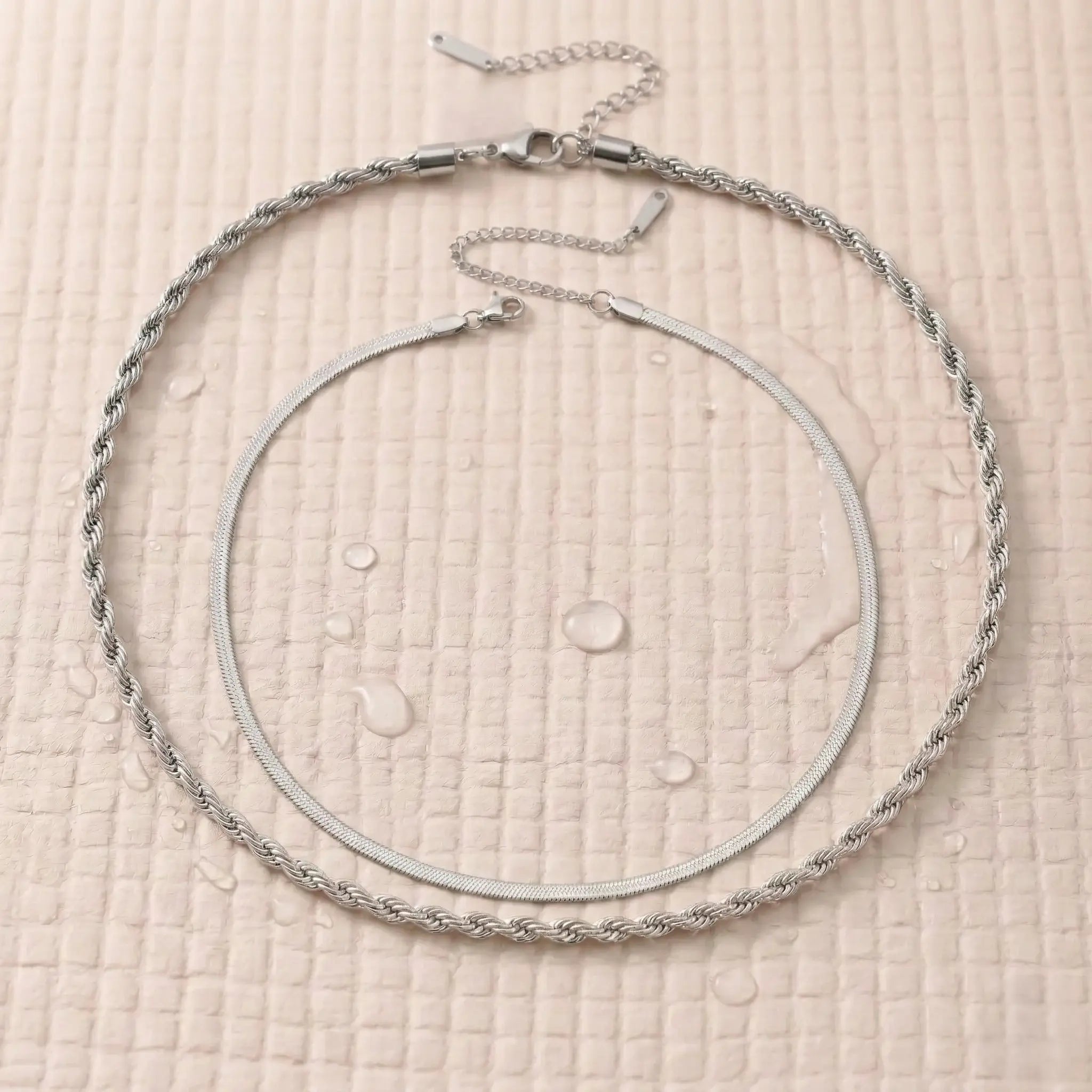 Silver-plated double chain necklace on a pink fitness mat.