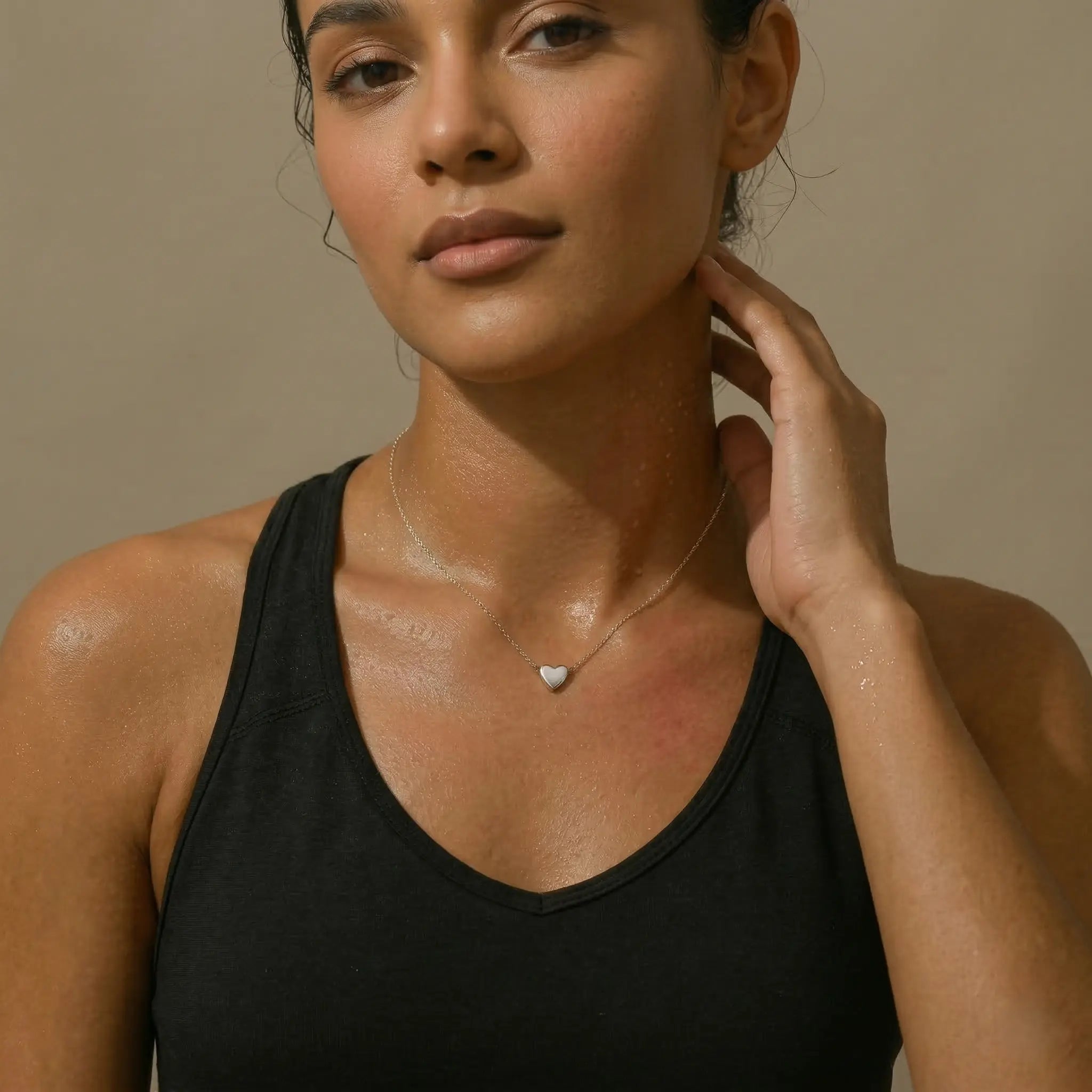 Woman wearing a black top with a silver necklace with a heart pendant.