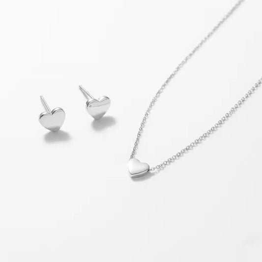 Silver heart-shaped necklace and matching stud earrings on a white background.