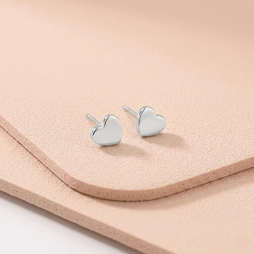 Waterproof heart silver stud earrings on a light pink fitness mat.
