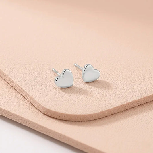 Waterproof heart silver stud earrings on a light pink fitness mat.