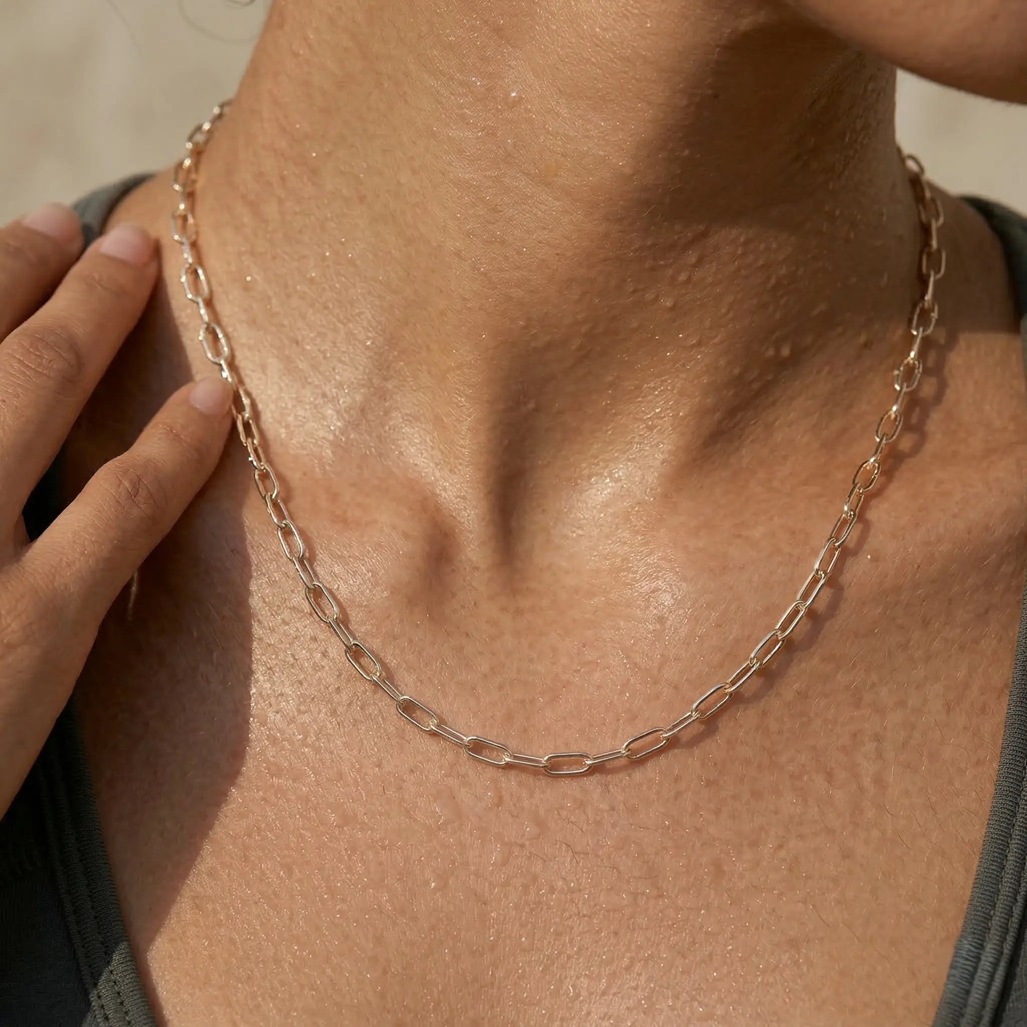 Close-up of a woman wearing a silver-plated chain necklace with a blurred background.
