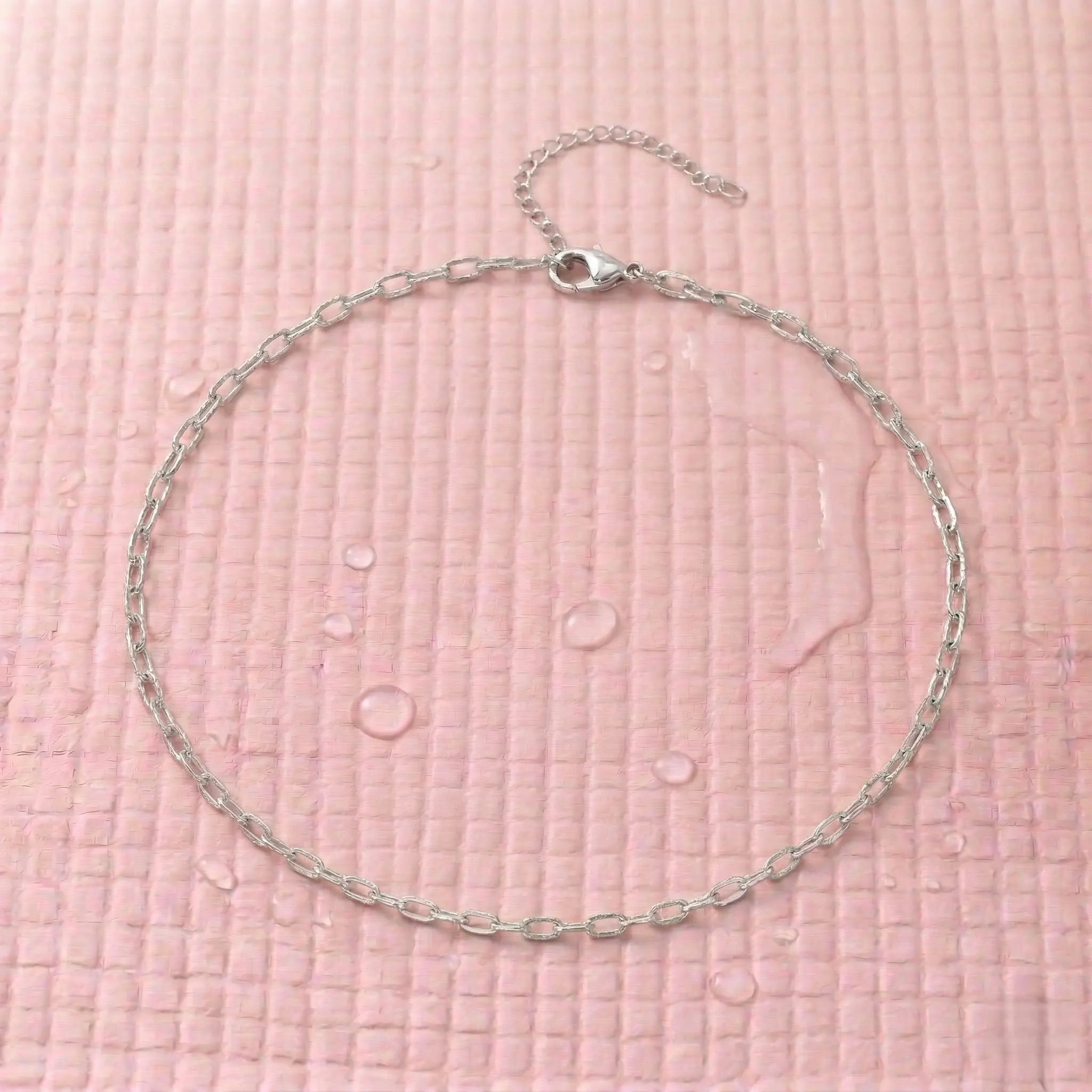 Waterproof silver chain necklace on a pink fitness mat.