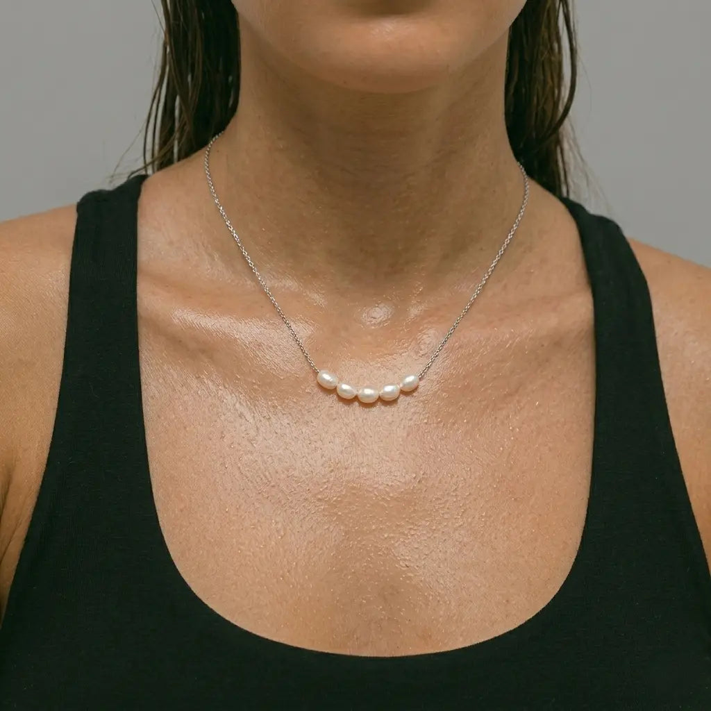 Silver pearl necklace worn by a woman against a neutral background.