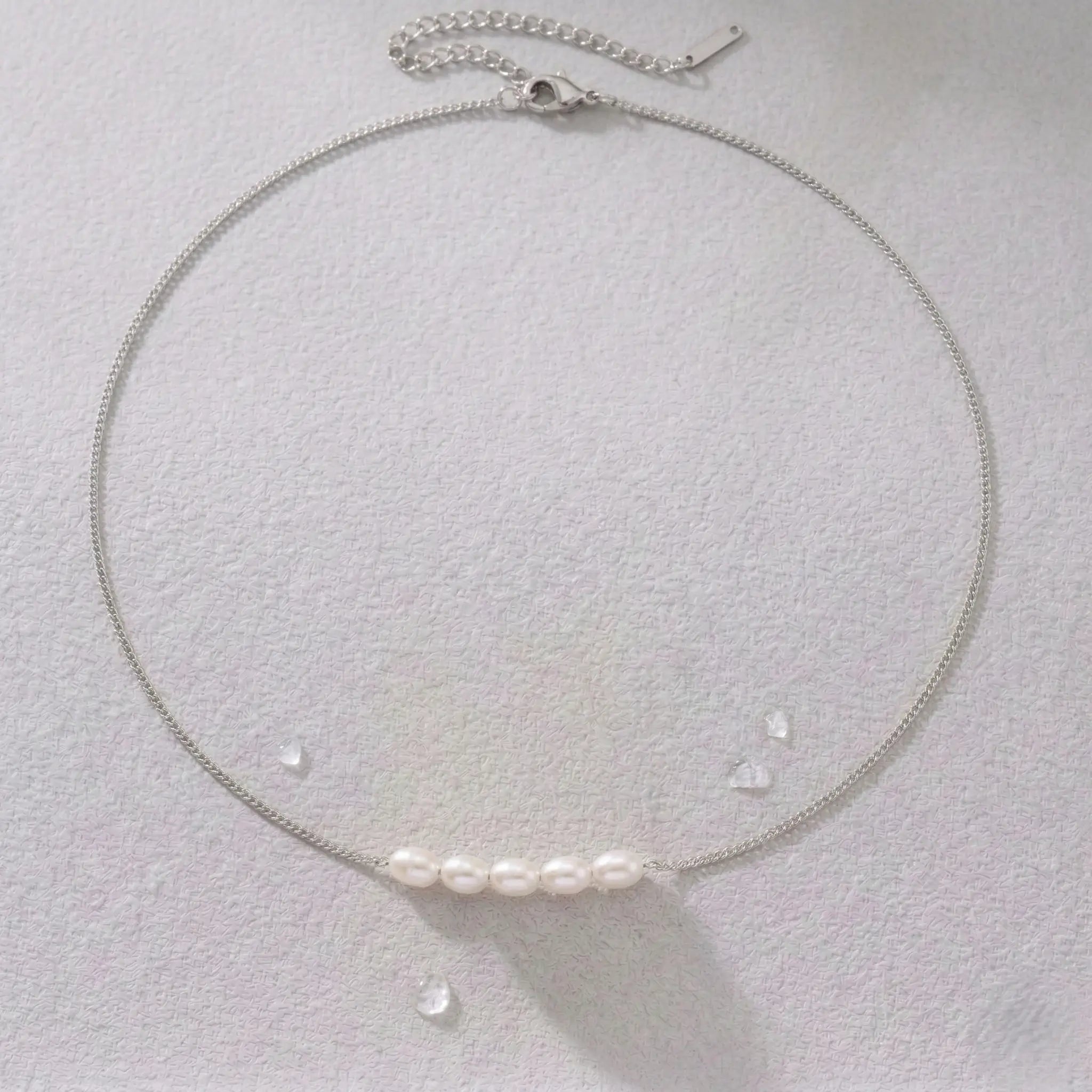 Silver-plated necklace with pearls on a light gray background.