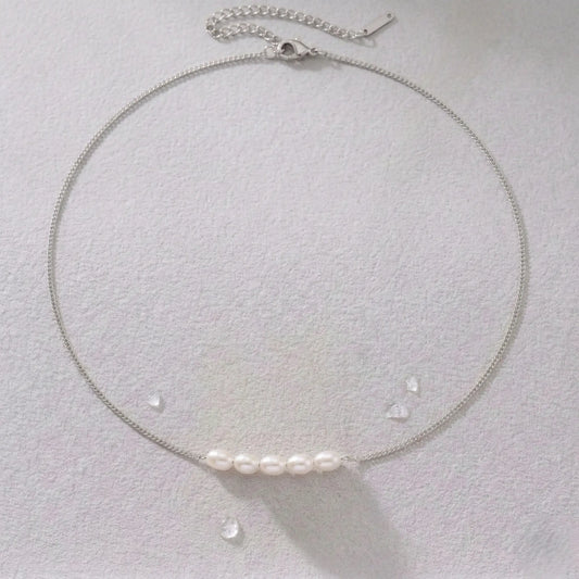Silver-plated necklace with pearls on a light gray background.