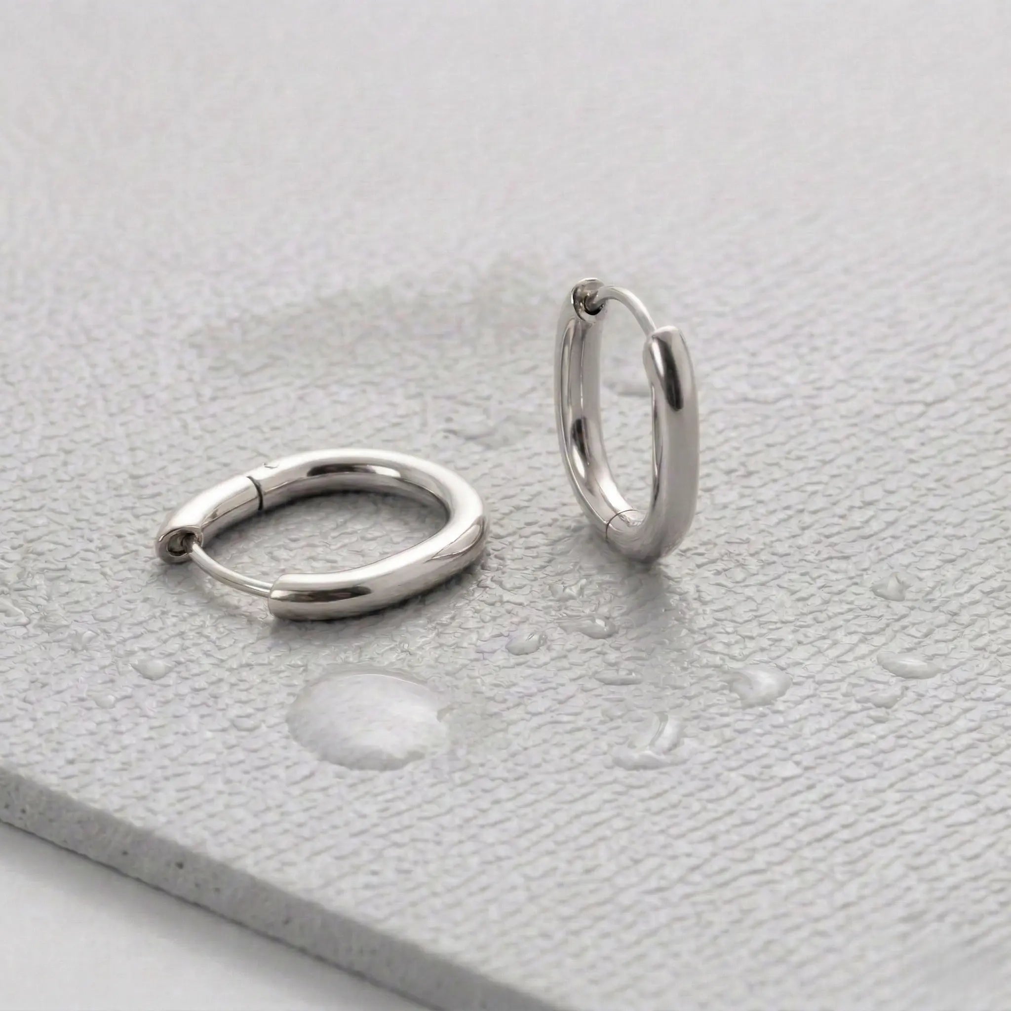 Pair of silver hoop earrings on a light gray fitness mat.