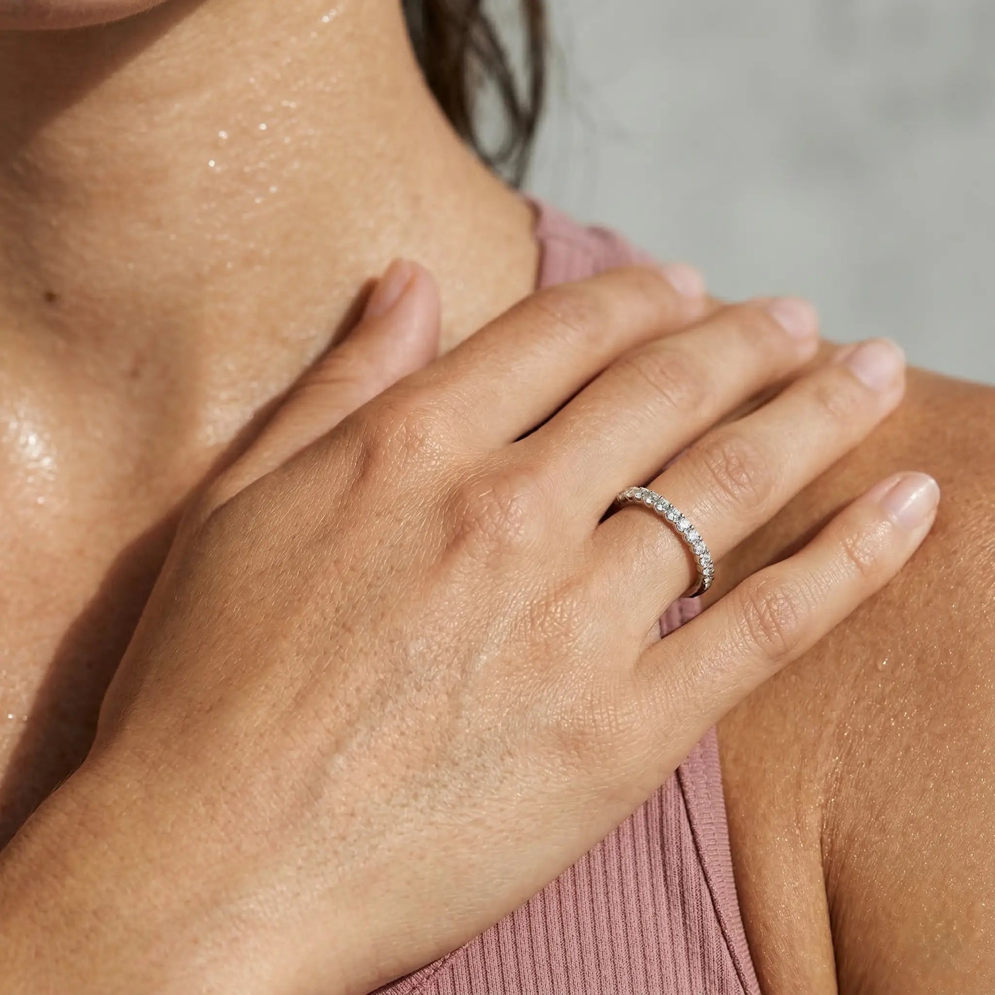 Close-up of a hand wearing a diamond ring on a blurred background.