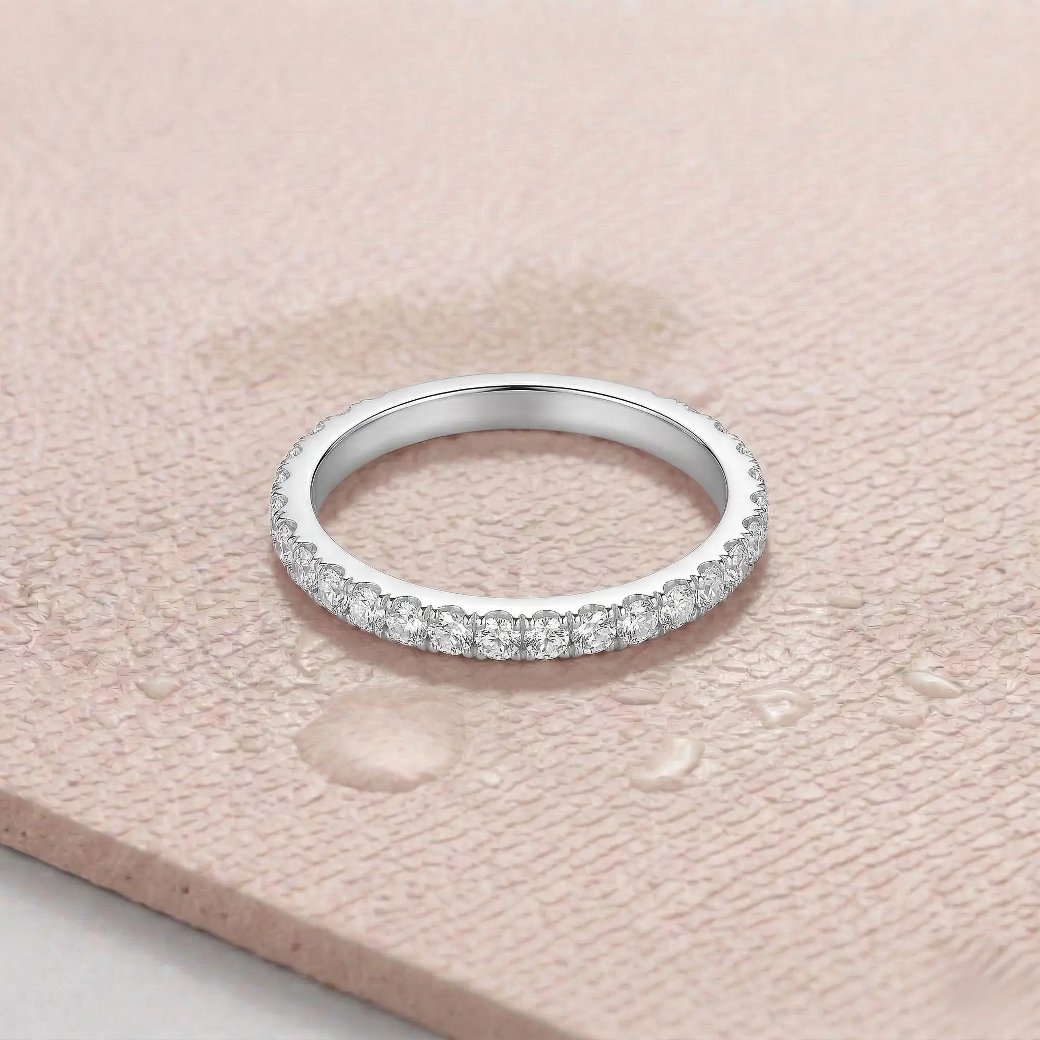 Silver ring with diamonds on a light pink fitness mat.