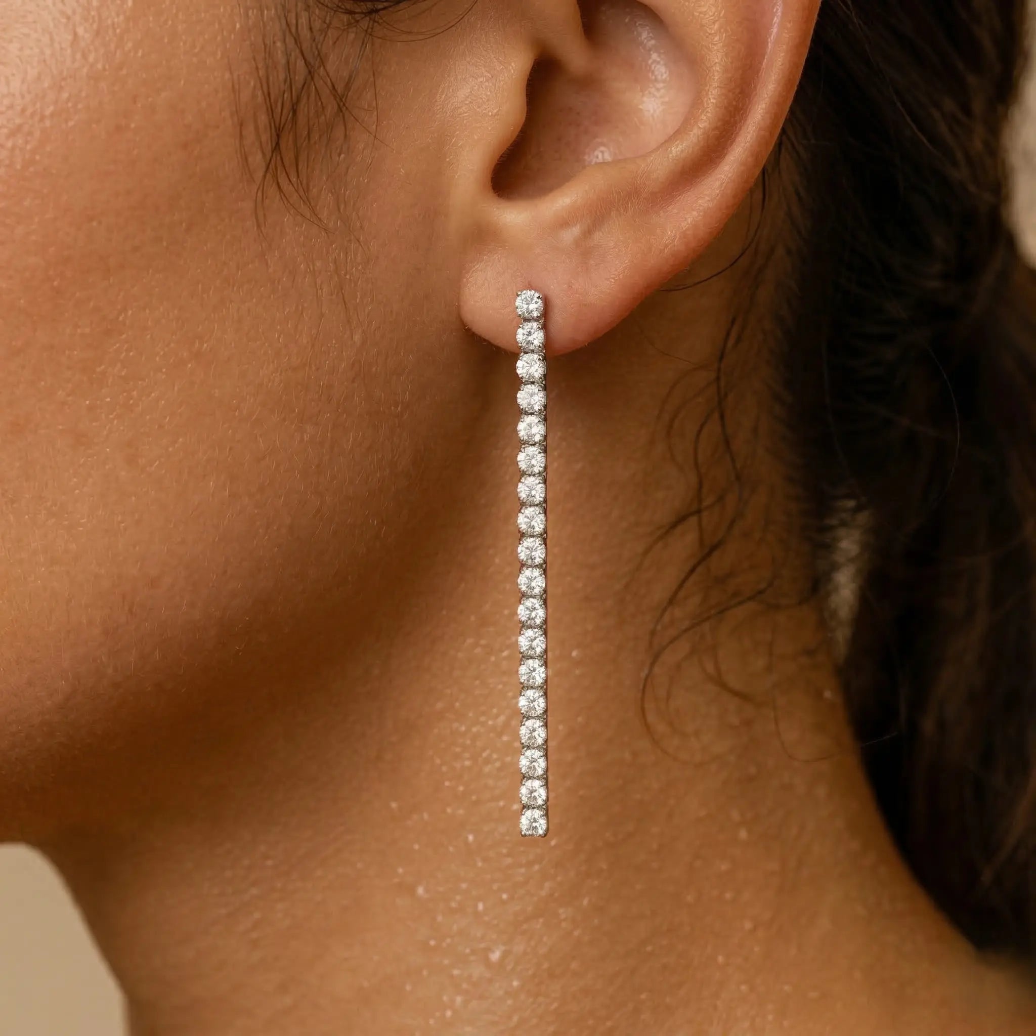 Close-up of an ear wearing a long diamond earring.