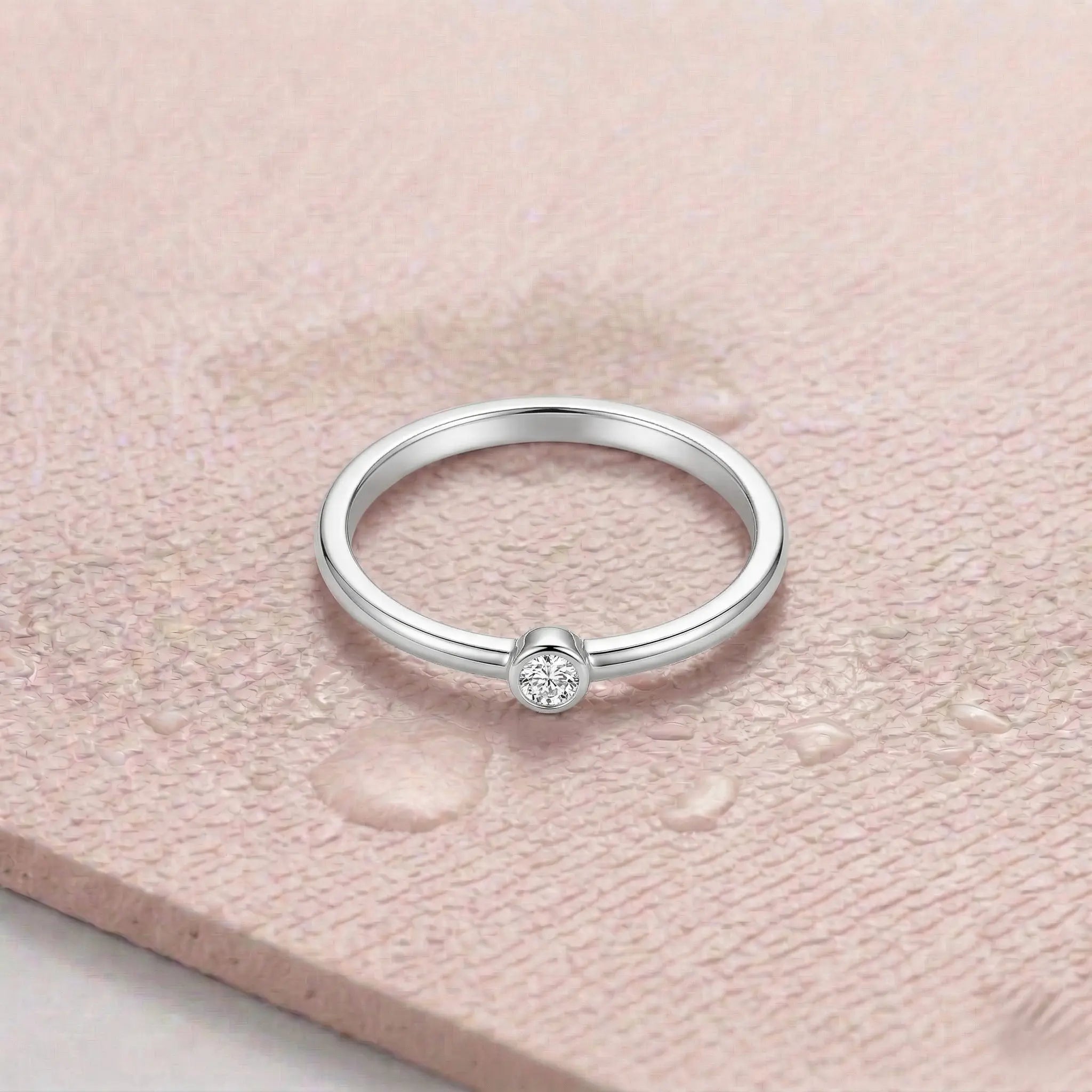Silver ring with a diamond on a light pink fitness mat.
