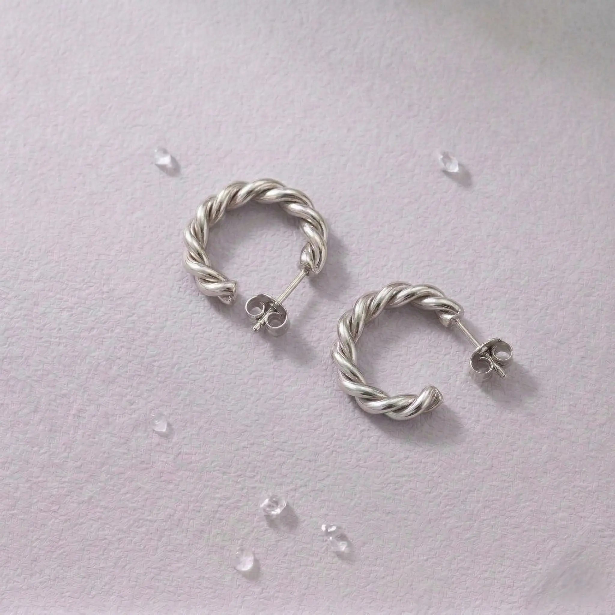Pair of waterproof silver hoop earrings on a light gray background.