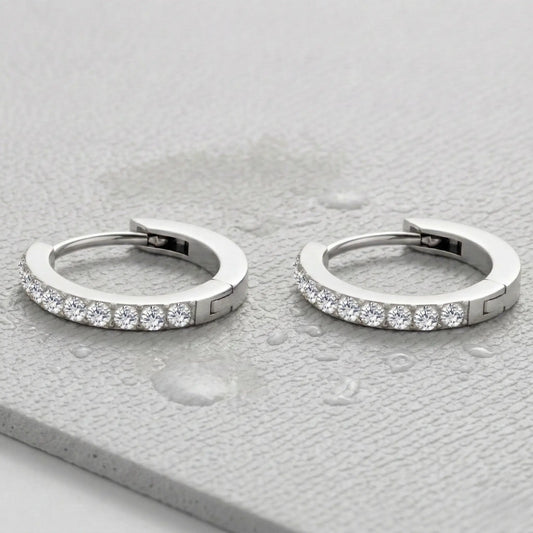 Silver-plated hoop earrings with embedded diamonds on a light gray fitness mat.