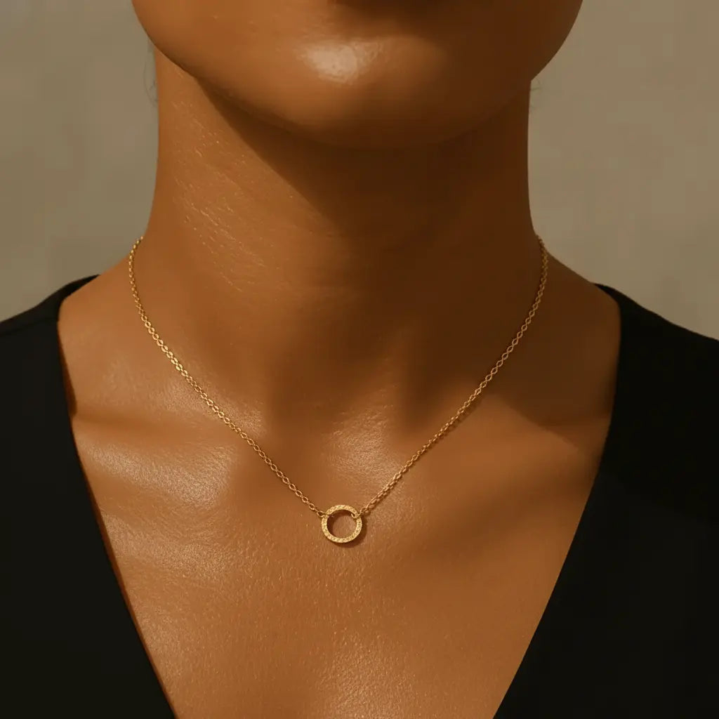 Gold necklace with a circular pendant on a woman wearing a black top