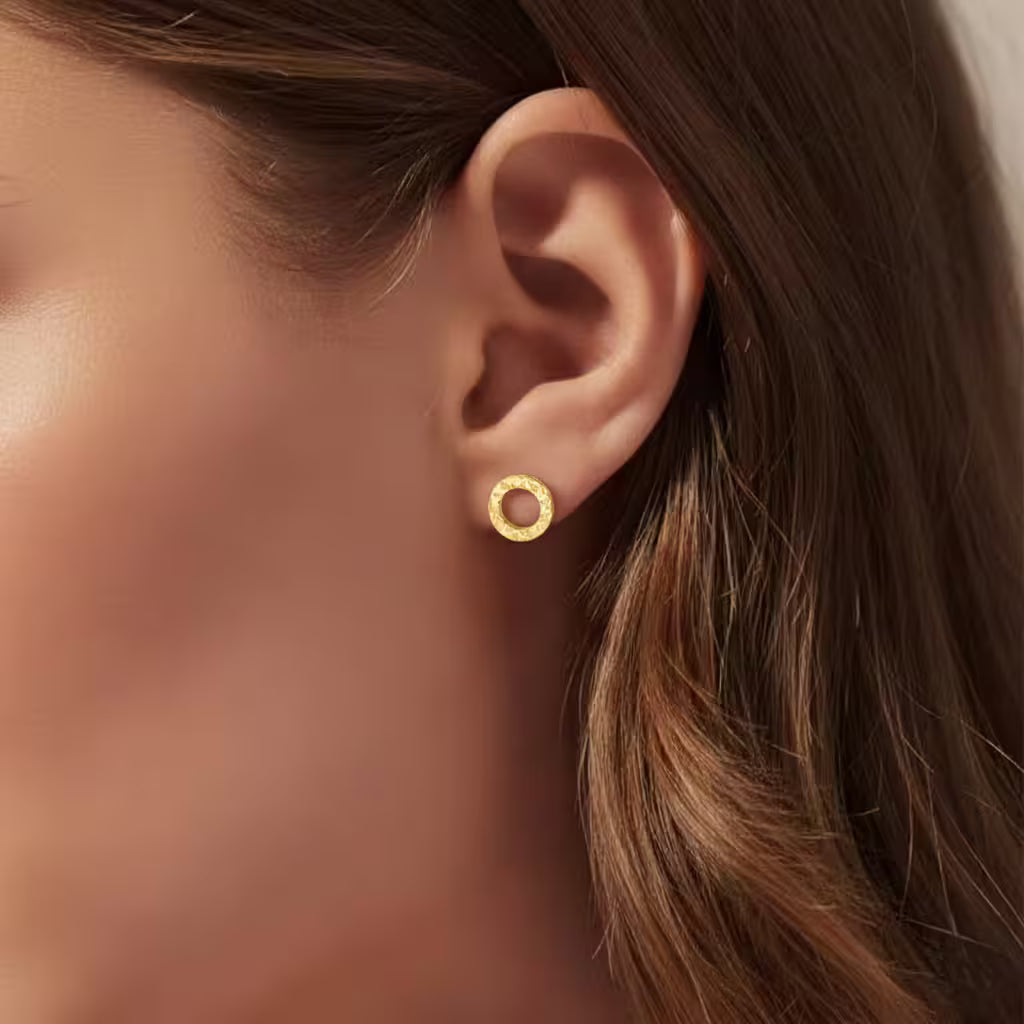 Close-up of an ear wearing a circle gold stud earring.