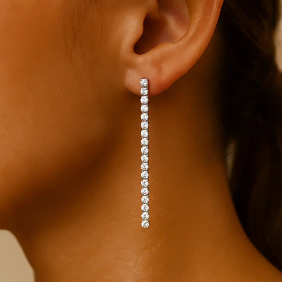 Close-up of an ear wearing a long silver diamond earring.