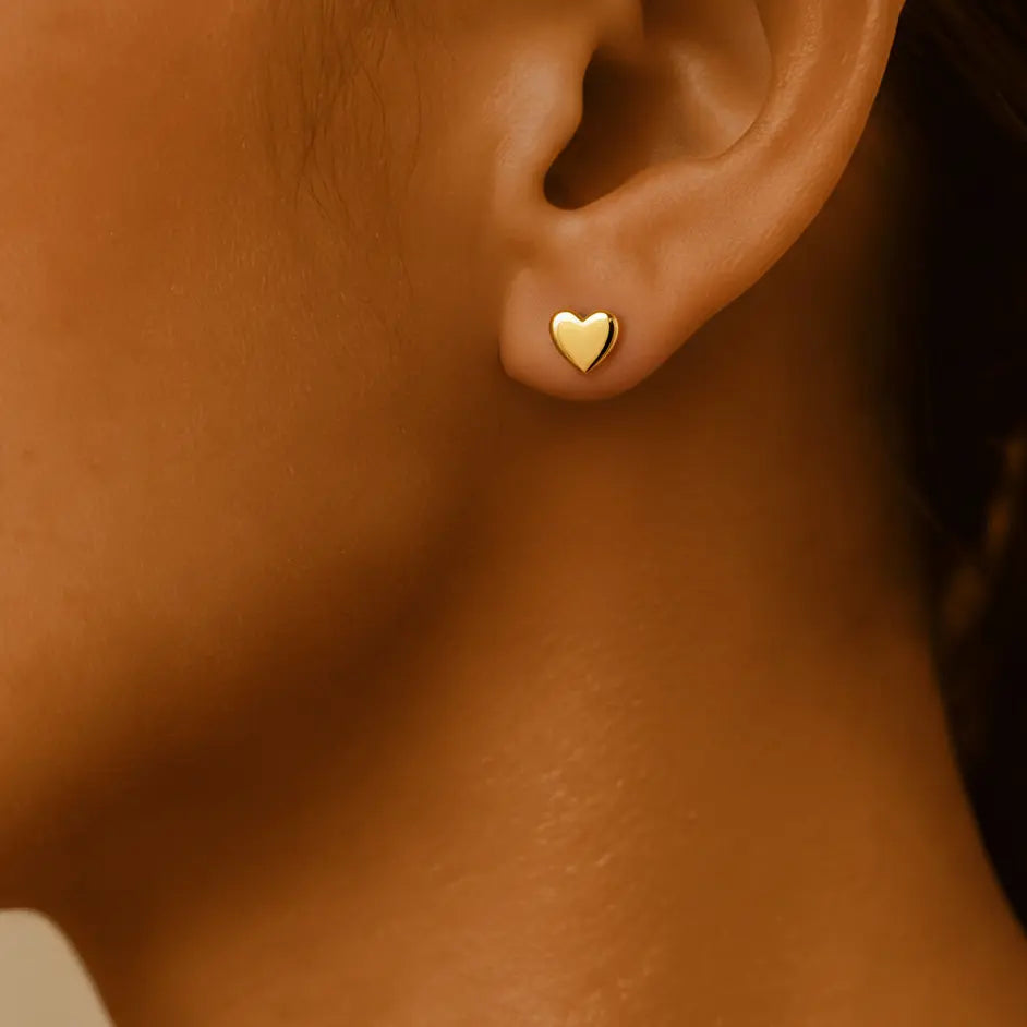 Waterproof gold heart studs earring on a women's ear.